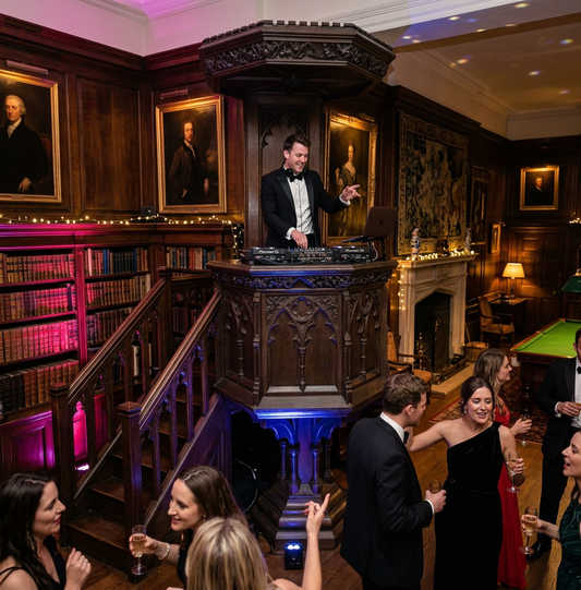 DJ in black tie plays music from a pulpit in a country house