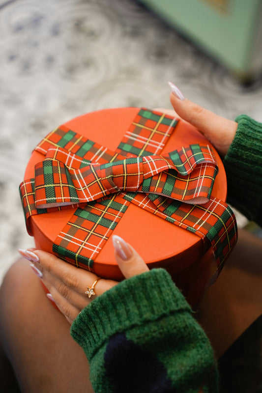 Lady holding present wrapped with a tartan bow