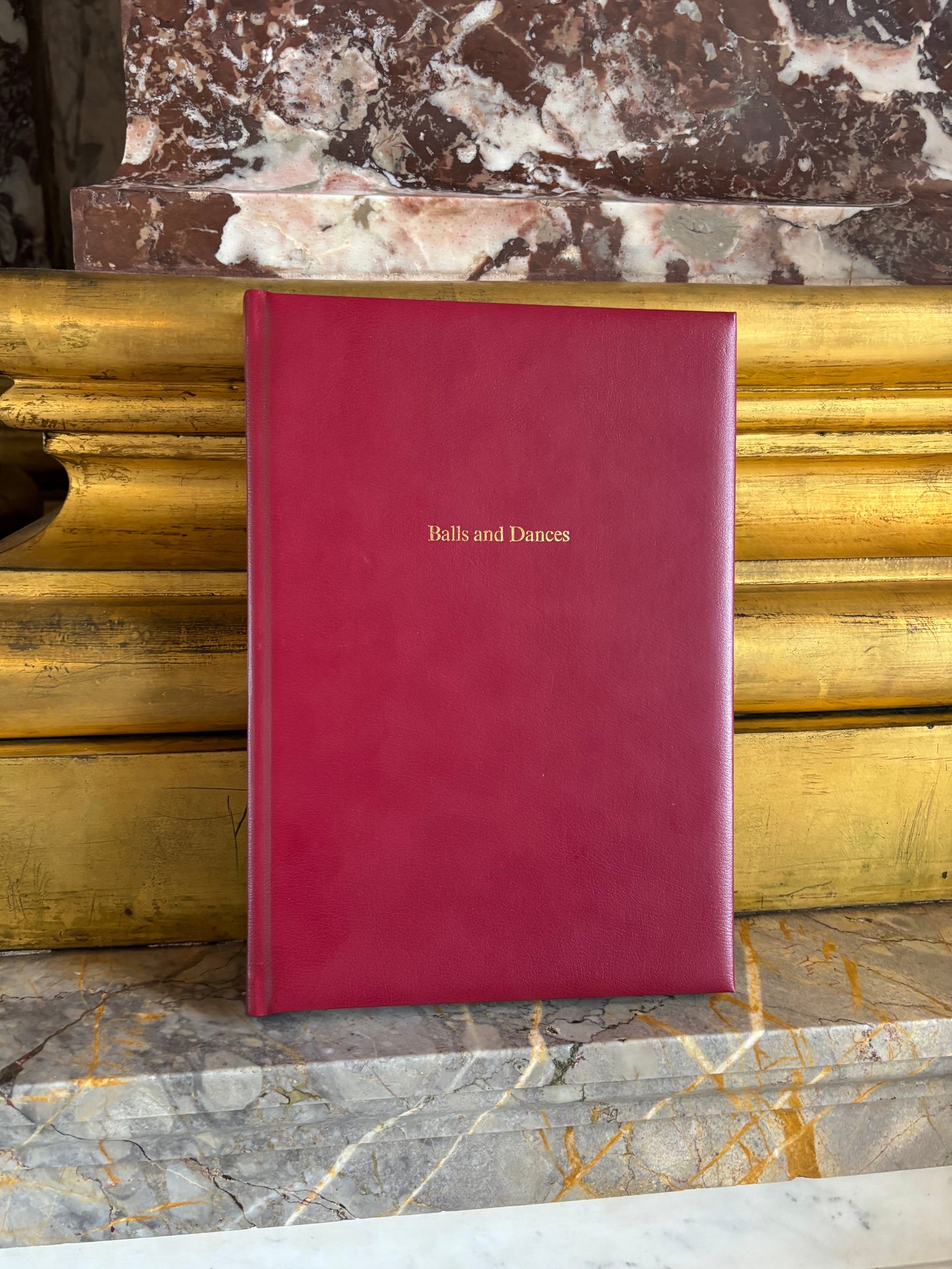 Red ballroom diary album on marble pillar with gold base